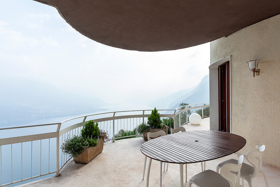 Terrace with oval table, white chairs and lake view