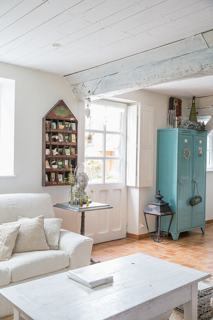 Helles Wohnzimmer im Landhausstil mit blauem Metallschrank und Holzbalken