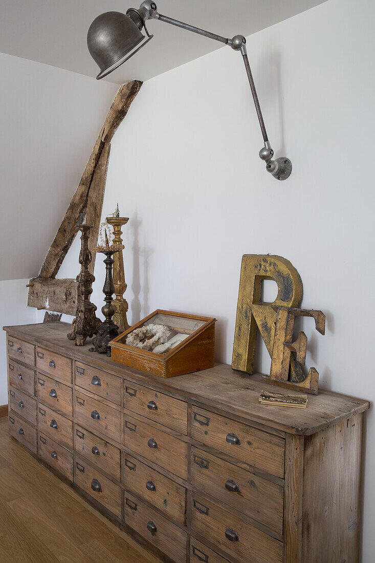 Wooden chest of drawers with drawers and rustic decoration under a swivelling lamp