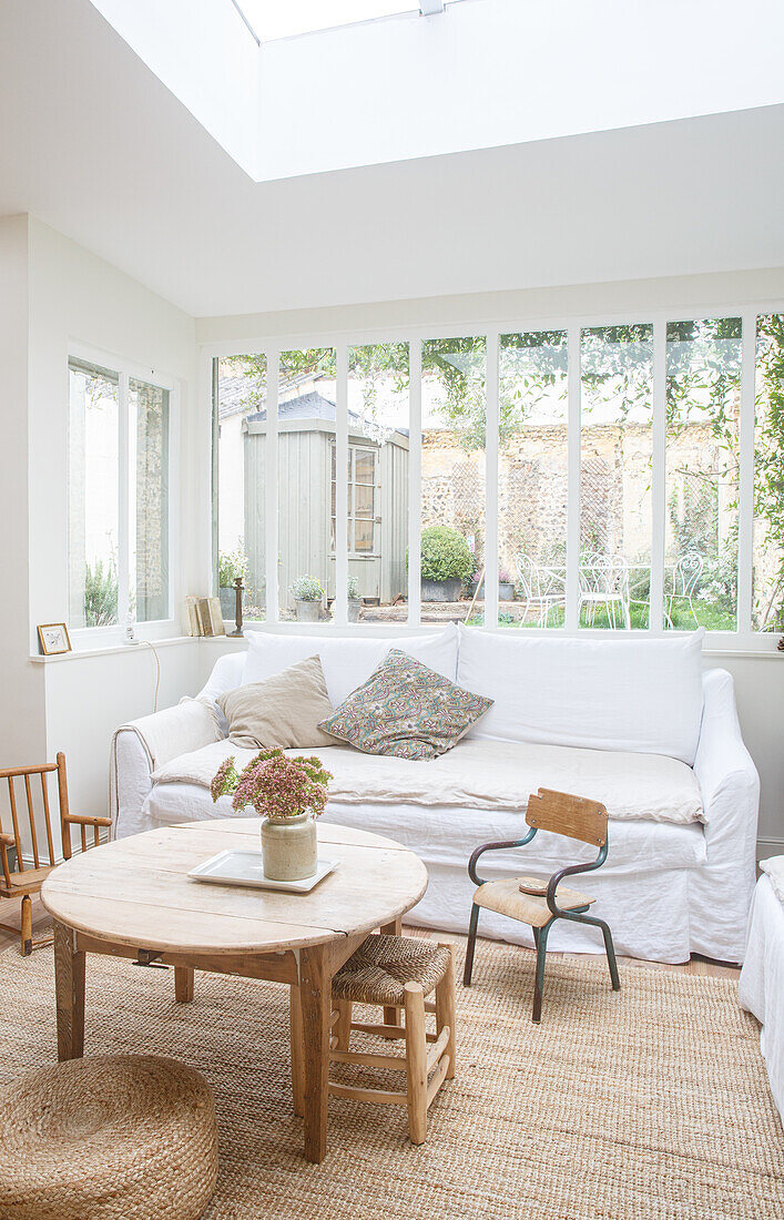 Bright room with white sofa, wooden furniture, lots of windows and skylight