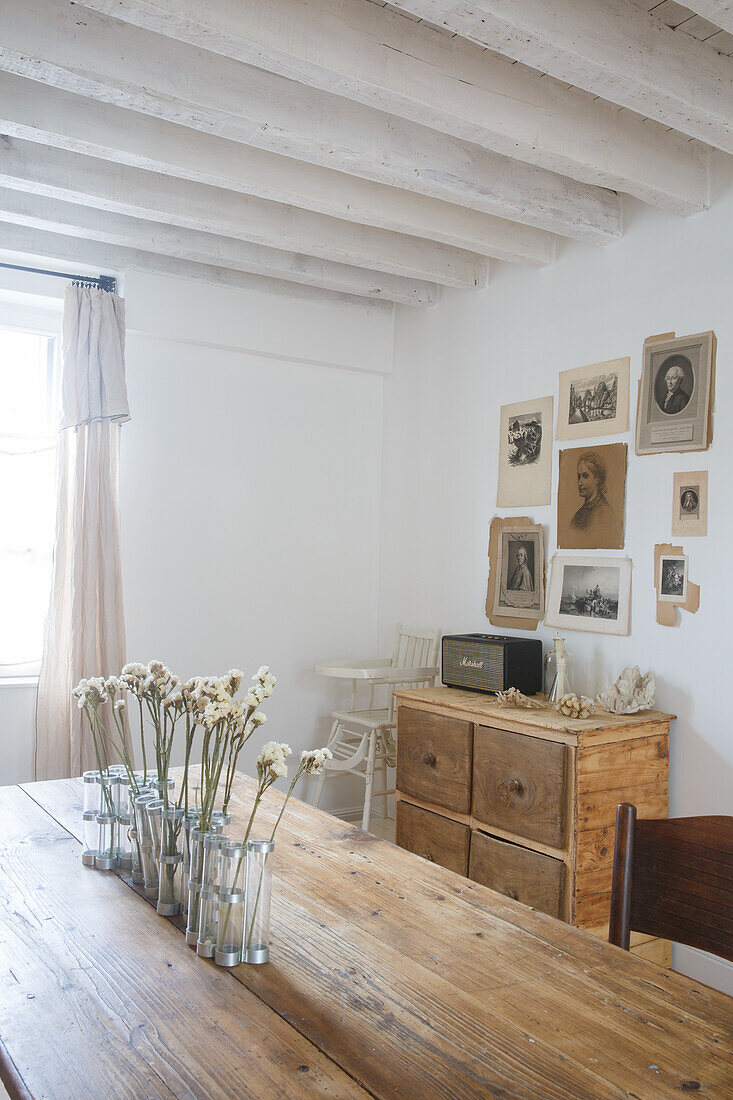 Dining room with wooden table, flowers and vintage photo wall