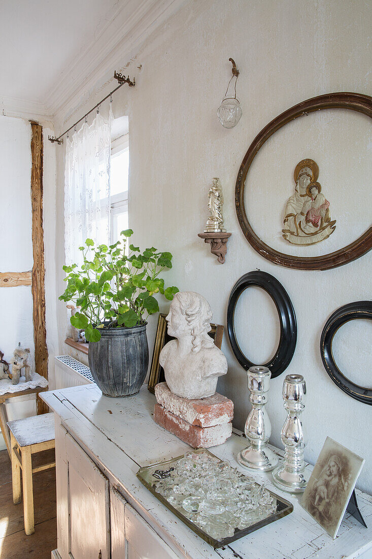 Sideboard in shabby chic look, bust, picture frame and green plant