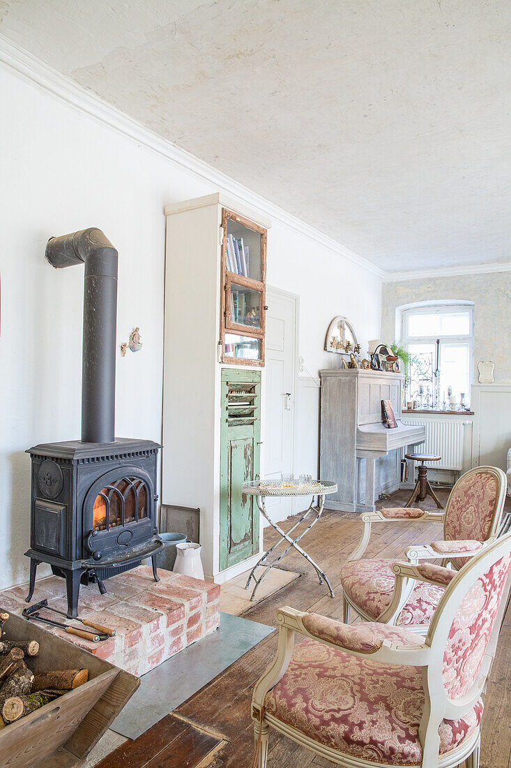 Cosy corner with wood-burning stove and antique armchairs in the living room