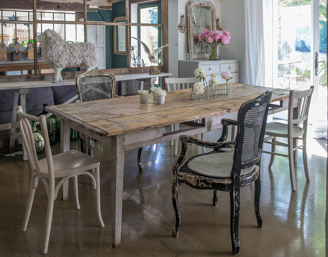 Dining table with various antique chairs in a rustic room