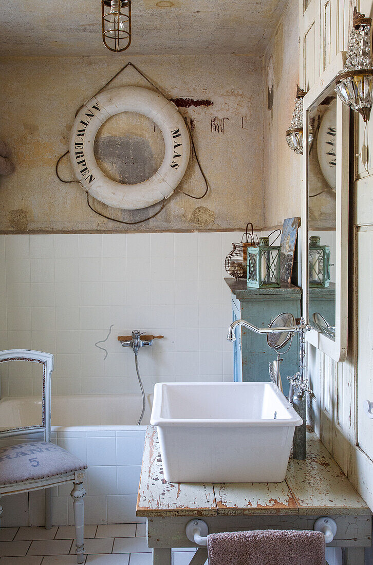 Vintage-Badezimmer mit Waschbecken auf rustikalem Holztisch und dekorativem Rettungsring an der Wand