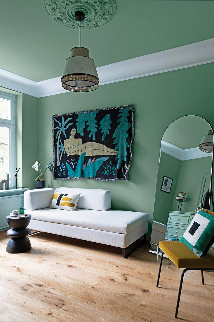 Living room with mint green walls and modern tapestry