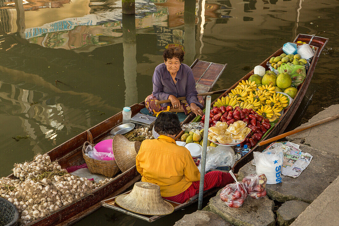 Social interaction between Thai vendors on their boats in the Damnoen Saduak Floating Market in Thailand.