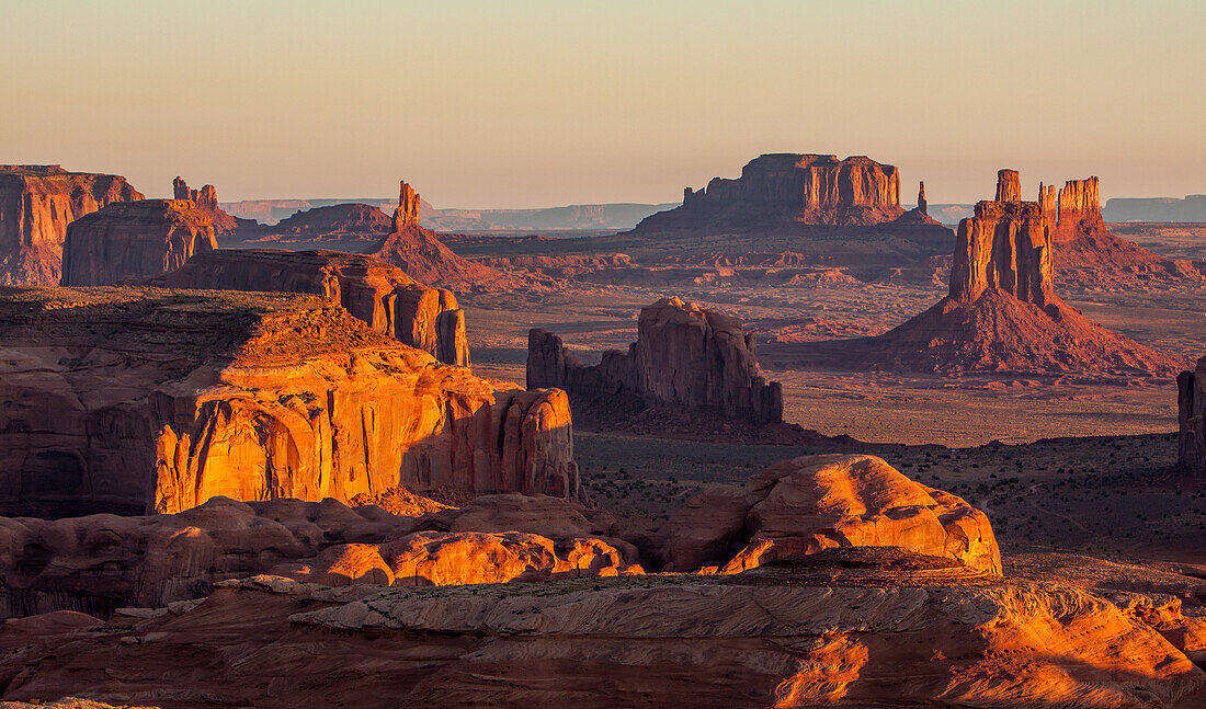 Sonnenaufgang im Monument Valley Navajo Tribal Park in Arizona. Blick von Hunt's Mesa. Rain God Mesa ist links. Rechts ist der East Mitten mit den Monumenten von Utah im Hintergrund zu sehen.