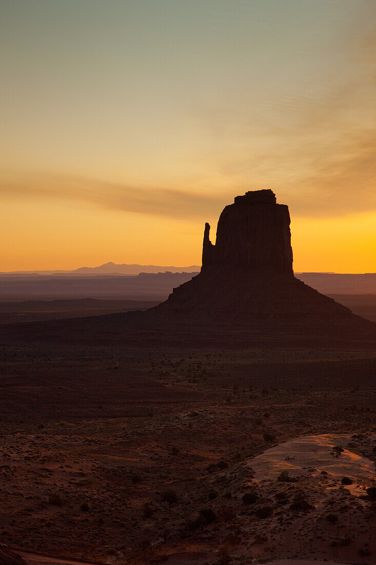 Colorful sunrise sky behind the East Mitten Butte in the Monument Valley Navajo Tribal Park in Arizona.