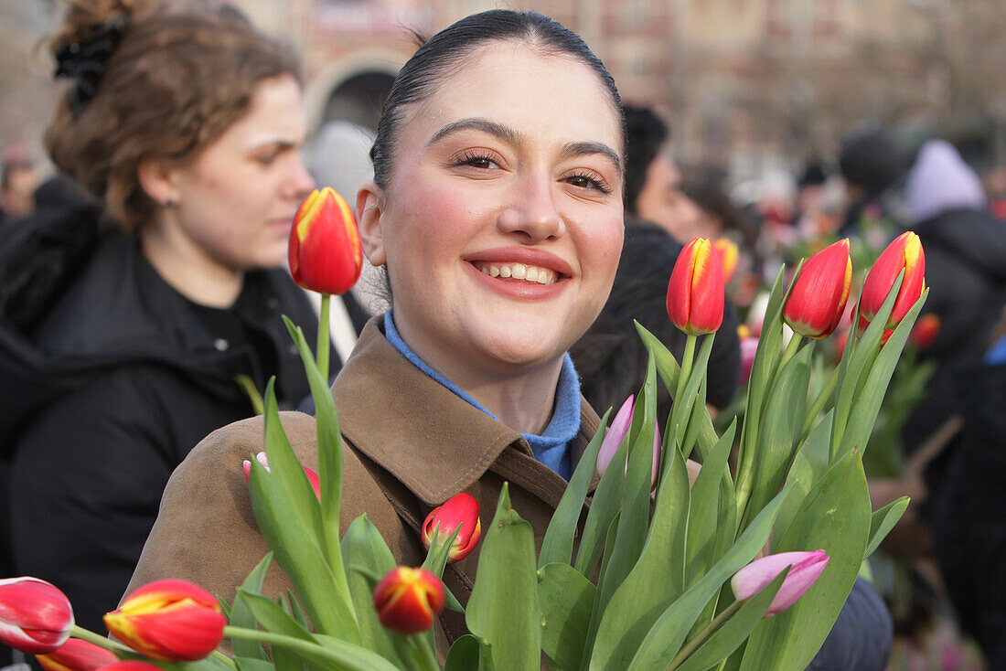 Ein Tourist hält einen Tulpenstrauß, während Tausende von Menschen während des Nationalen Tulpentages auf dem Museumsplatz in der Nähe des Rijskmuseums am 20. Januar 2024 in Amsterdam, Niederlande, kostenlos Tulpen pflücken. Heute ist der offizielle Beginn der Tulpensaison mit einem speziellen Tulpengarten, in dem die Menschen kostenlos Tulpen pflücken können. In diesem Jahr wird der 12. Jahrestag des von den niederländischen Tulpenzüchtern organisierten Pflückgartens besonders gefeiert. Der Amsterdamer Museumsplatz ist mit rund 200.000 Tulpen gefüllt. Diese Tulpen werden speziell zu einem rie