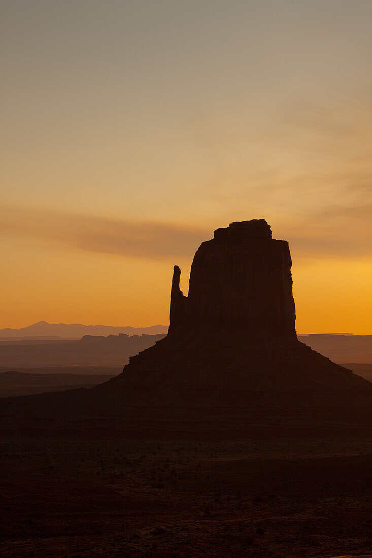 Pastel sunrise sky behind the East Mitten Butte in the Monument Valley Navajo Tribal Park in Arizona.