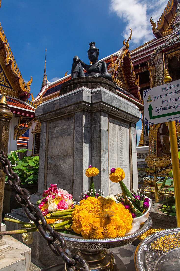 Eine Votivgabe am Sockel der Statue des Einsiedlerdoktors Chewaka Komarapach im Großen Palast in Bangkok, Thailand. Chewaka Komarapach ist der Schutzheilige der Medizin in Thailand.