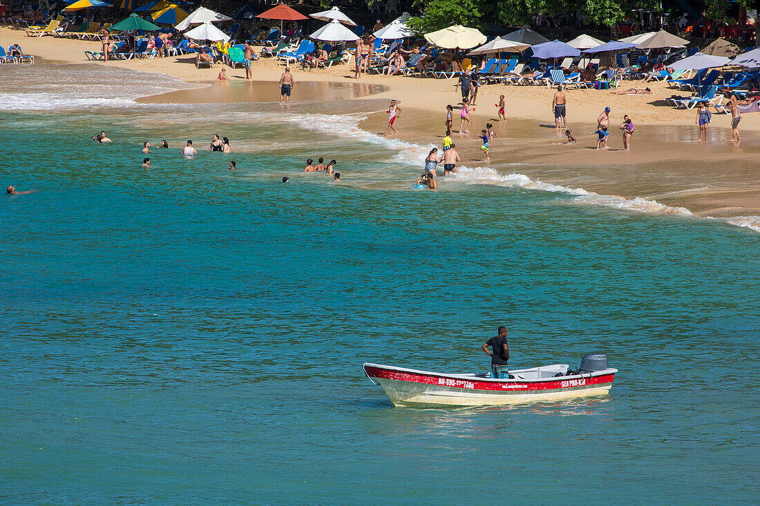 Touristen am Strand der Bucht von Sosua in der Dominikanischen Republik