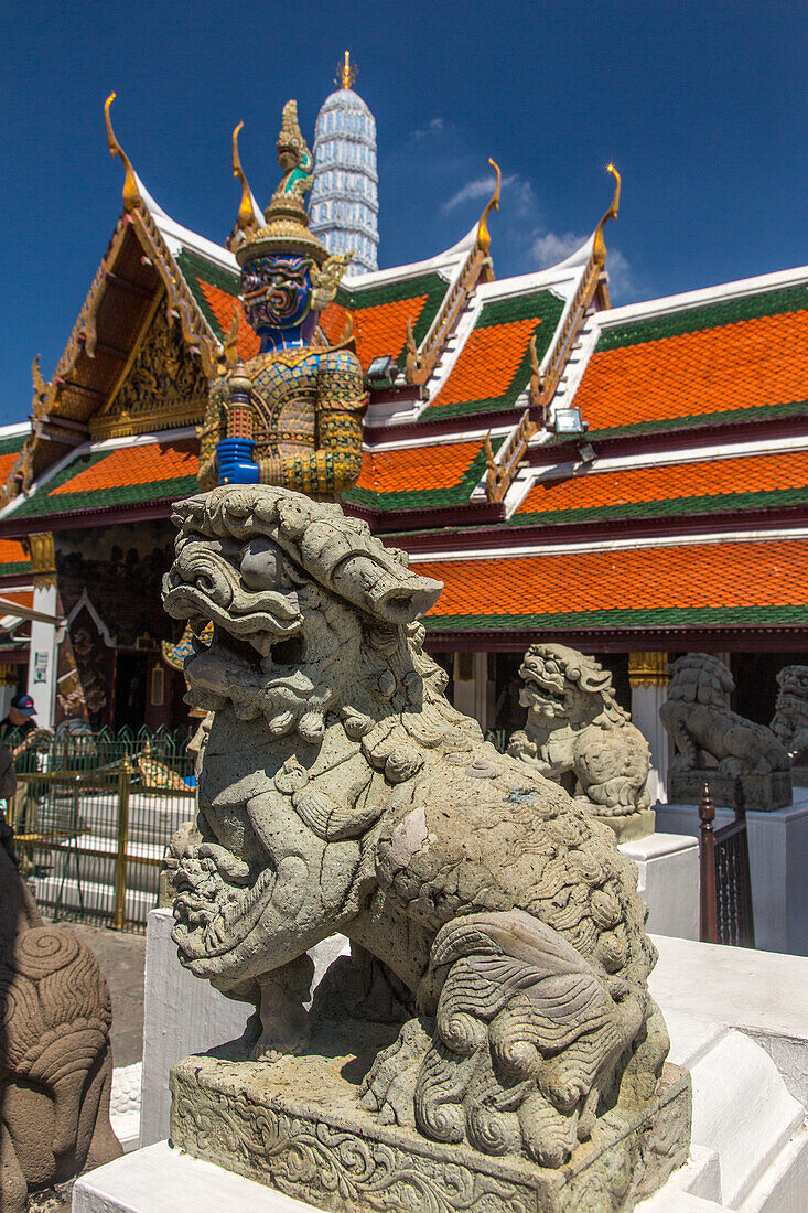 A lion and a yaksha statue at the Temple of the Emerald Buddha complex at the Grand Palace grounds in Bangkok, Thailand.