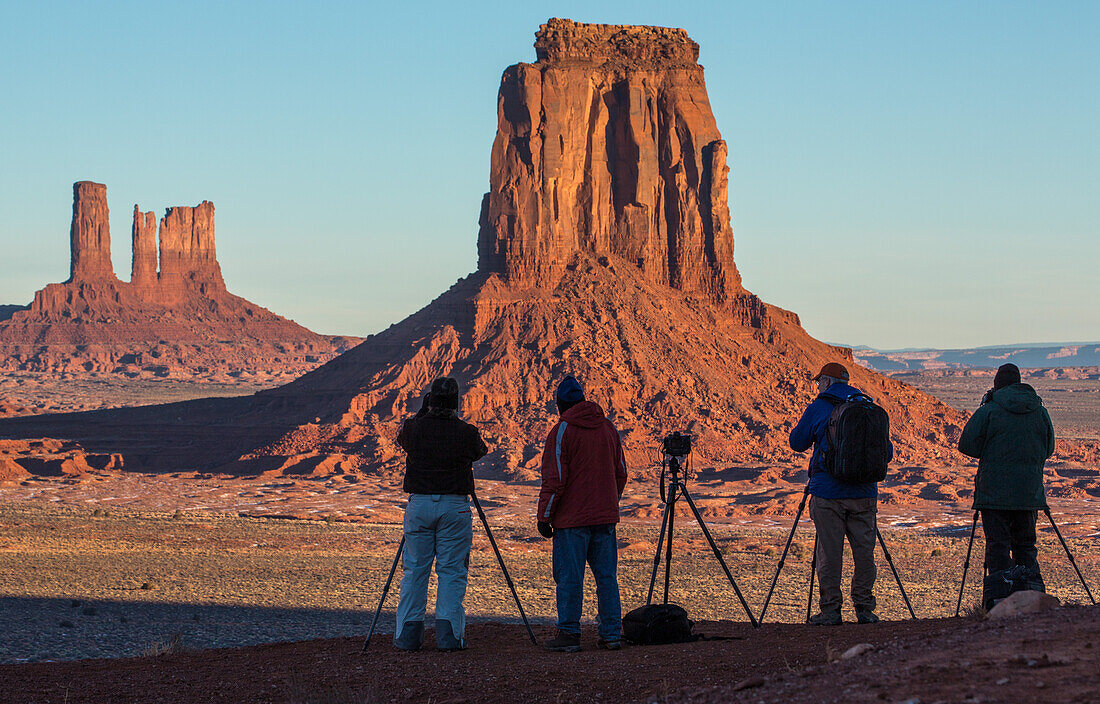 Photographers at the North Window view of the Utah monuments in the Monument Valley Navajo Tribal Park in Arizona. L-R: Castle Butte, Bear and Rabbit, Stagecoach & East Mitten Butte.