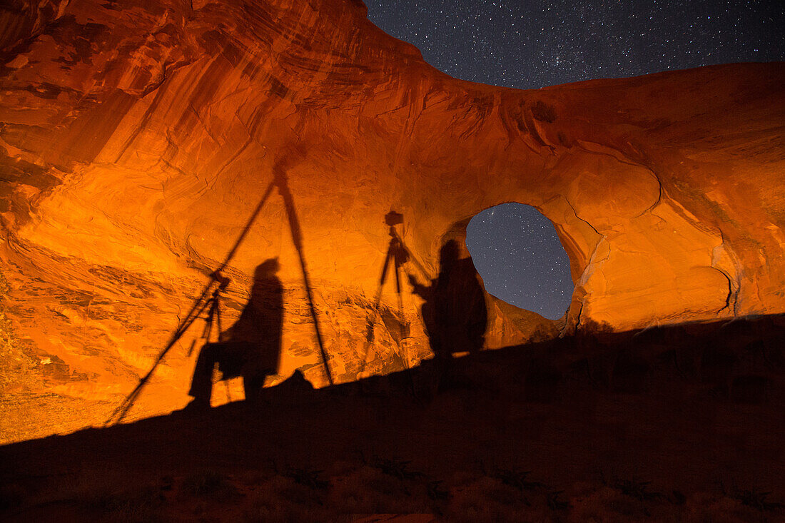 Photographers' shadows on the wall of the Ear of the Wind Arch at night in the Monument Valley Navajo Tribal Park in Arizona.