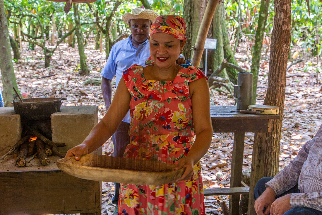 A worker demonstrates the traditional method of winnowing dried cacao beans on a cacao plantation. Dominican Republic.