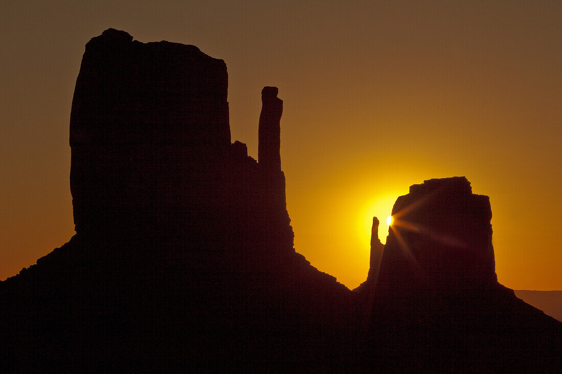 Sun behind the East Mitten in the Monument Valley Navajo Tribal Park in Arizona.