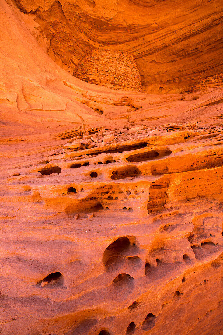 An Ancestral Puebloan ruin inside Honeymoon Arch in Mystery Valley in the Monument Valley Navajo Tribal Park in Arizona. In front is tafoni or rock lace erosion in the sandstone.