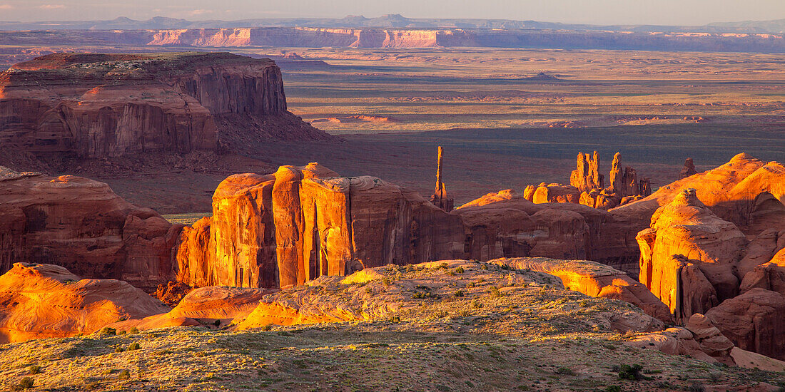 Sonnenuntergangslicht auf dem Totempfahl und dem Yei Be Chei im Monument Navajo Valley Tribal Park in Arizona. Blick von Hunt's Mesa. Die Bear's Ears sind in der Ferne über Cedar Mesa zu sehen.