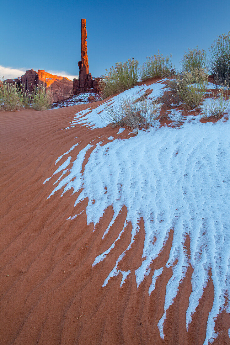 The Totem Pole with snow and rippled sand in the Monument Valley Navajo Tribal Park in Arizona.
