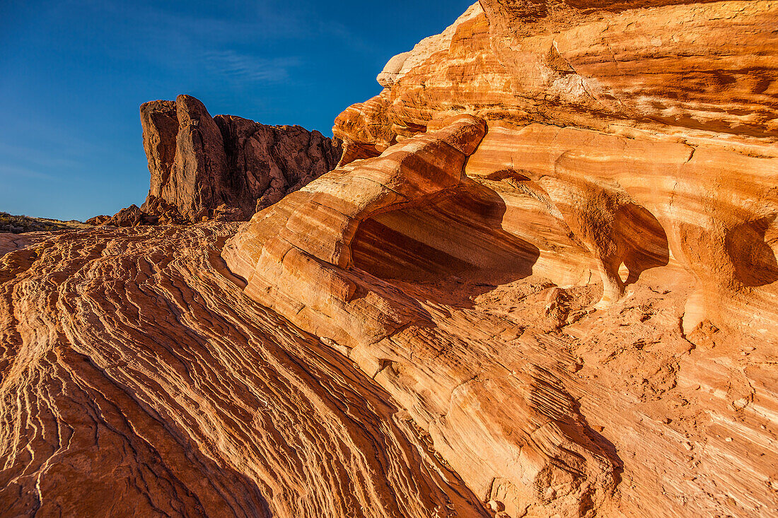 A small piano-leg arch in a colorful eroded Aztec sandstone formation in Valley of Fire State Park in Nevada.