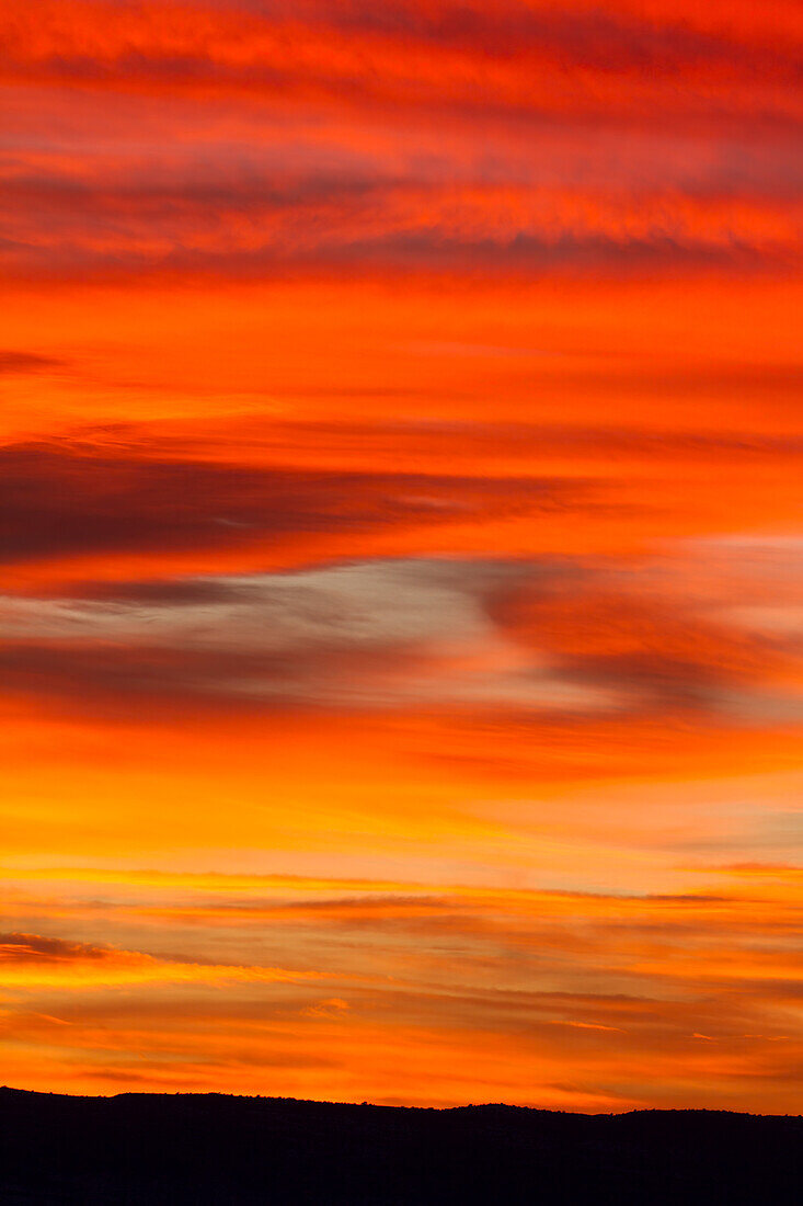 Feurig rote Wolken bei Sonnenuntergang über der Canyonlandschaft bei Moab, Utah