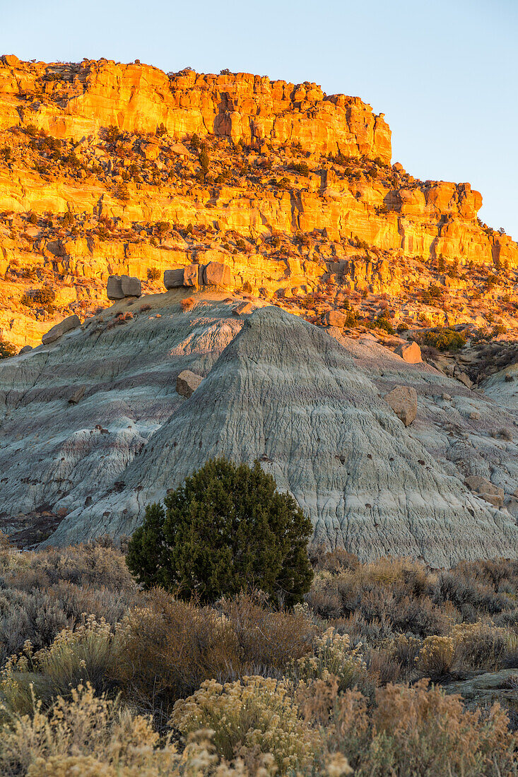 Sunset on the sandstone cliffs in northwestern New Mexico, USA. In front is an eroded shale hillside.