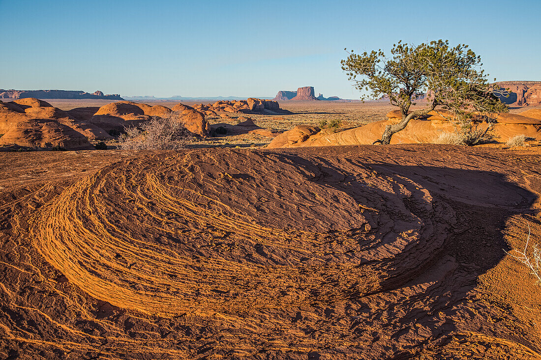 Eroded sandstone in Mystery Valley in the Monument Valley Navajo Tribal Park in Arizona. The Utah monuments are behind.