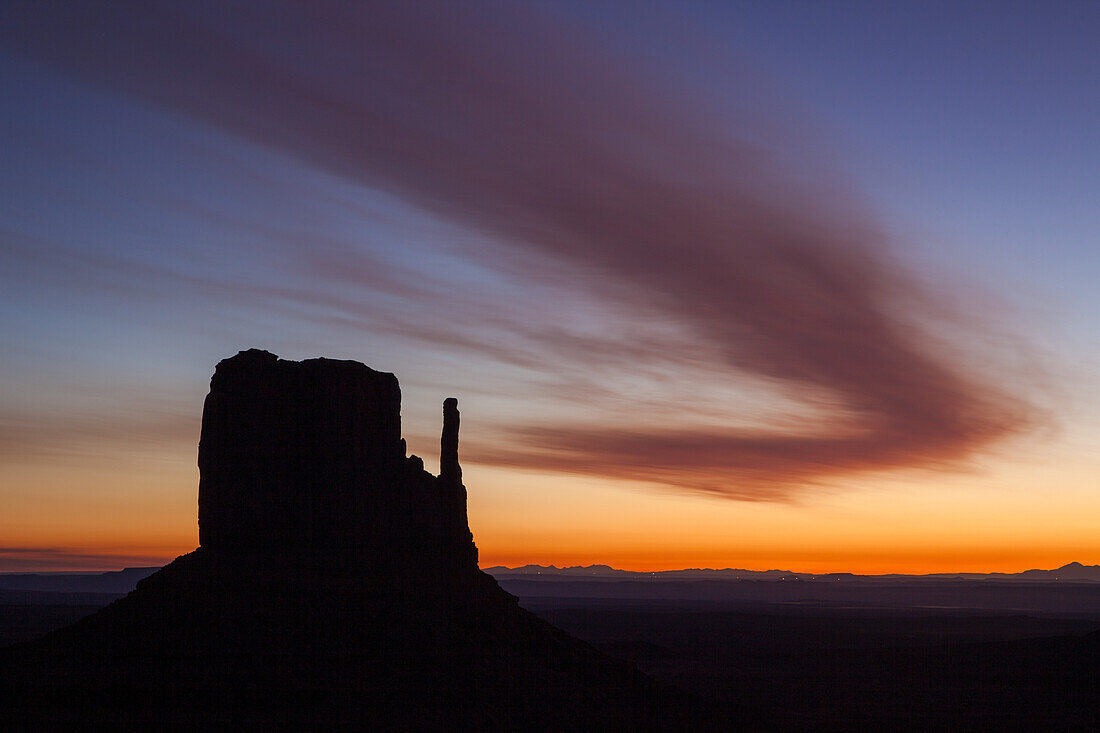 Gebogene Wolke über dem West Mitten Butte vor Sonnenaufgang im Monument Valley Navajo Tribal Park in Arizona