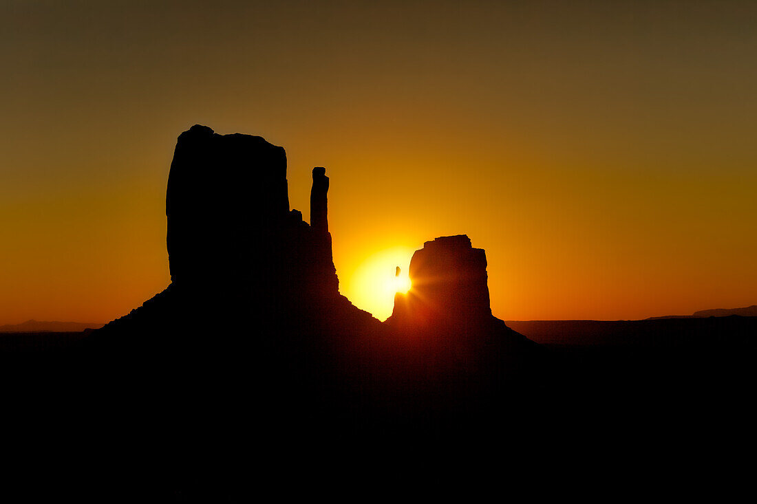 Sun behind the East Mitten in the Monument Valley Navajo Tribal Park in Arizona.