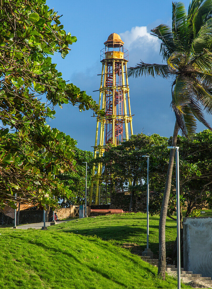 Der gusseiserne Leuchtturm von Puerto Plata wurde 1879 im heutigen La Puntilla Park in Puerto Plata, Dominikanische Republik, erbaut. Er ist 24,38 Meter hoch. Im Vordergrund ist ein Amphitheater im Park zu sehen.