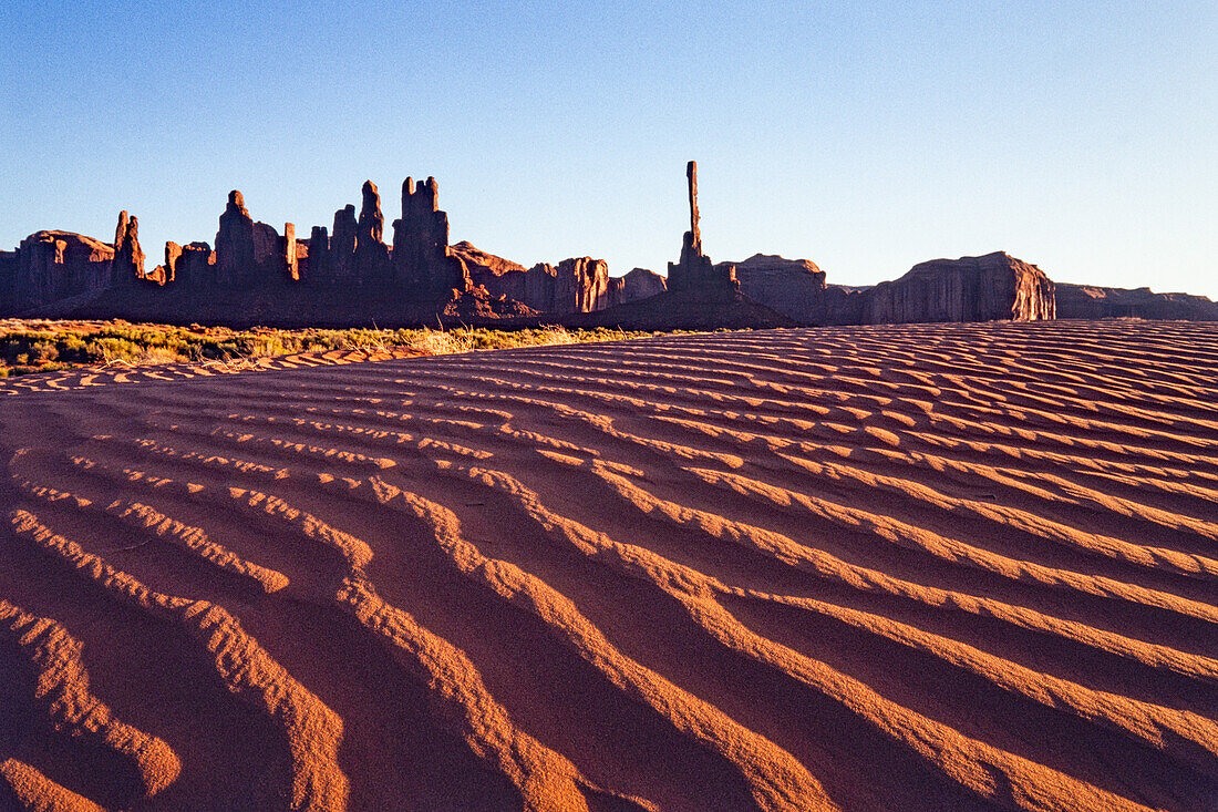 The Totem Pole & Yei Bi Chei with rippled sand dunes in the Monument Valley Navajo Tribal Park in Arizona.