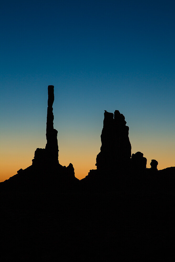 Der Totempfahl und der Yei Bi Chei in der Silhouette vor Sonnenaufgang im Monument Valley Navajo Tribal Park in Arizona