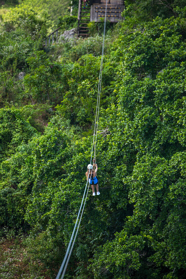 Eine junge Frau beim Ziplining über dem Regenwald in der Nähe von Sosua in der Dominikanischen Republik