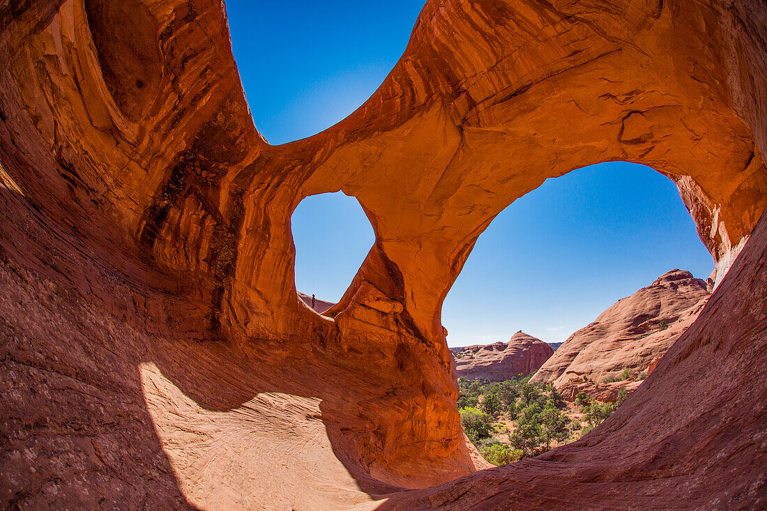 A Navajo guide stands in Spiderweb Arch, a large natural double arch in the Monument Valley Navajo Tribal Park in Arizona.