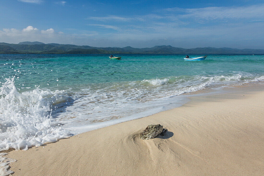 Motor launches are moored in the clear shallow water around Cayo Arena or Paradise Island. Behind is Monte Cristi National Park in the Dominican Republic., Hispaniola.