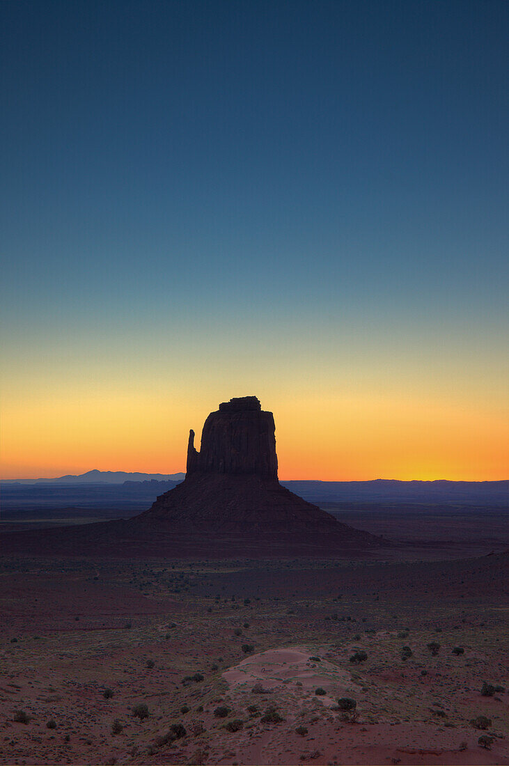 Colorful sunrise sky behind the East Mitten Butte in the Monument Valley Navajo Tribal Park in Arizona.