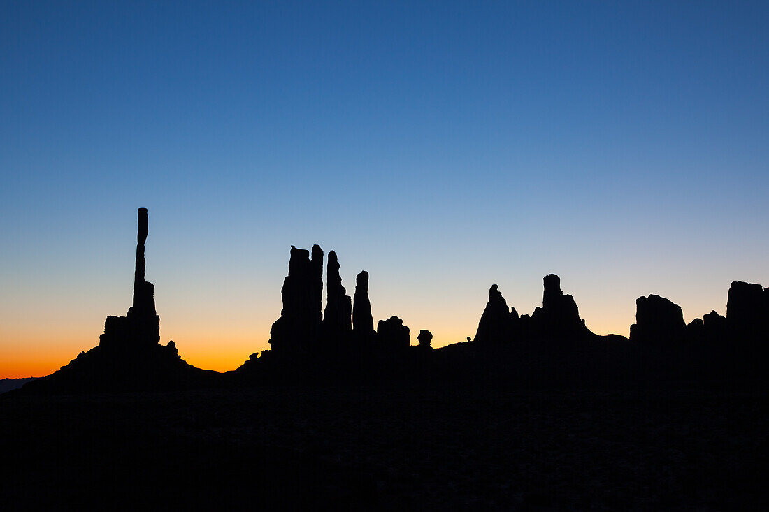 The Totem Pole and the Yei Bi Chei in silhouette before dawn in the Monument Valley Navajo Tribal Park in Arizona.