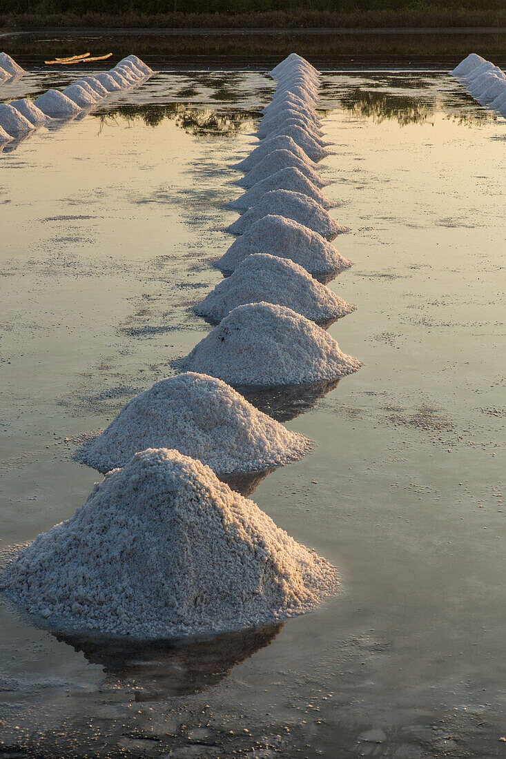 Salzhaufen bilden geometrische Muster auf der Salzpfanne in einer traditionellen Verdunstungssalzfarm in Samut Sakhon, Thailand