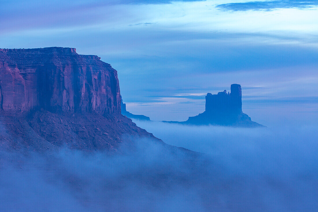 Nebel in der Morgendämmerung am Fuße von Elephant Butte, Castle Butte und der Postkutsche im Monument Valley Navajo Tribal Park in Arizona und Utah
