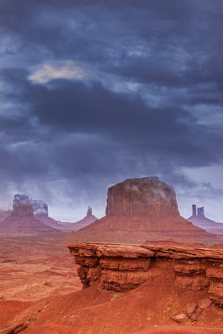 Stormy view of Monument Valley from John Ford Point in the Monument Valley Navajo Tribal Park in Arizona. L-R: Sentinal Mesa with the West Mitten in front, Big Indian Chief obscured by cloud, Merrick Butte, the Castle, and the Stagecoach. John Ford Point is in the foreground.