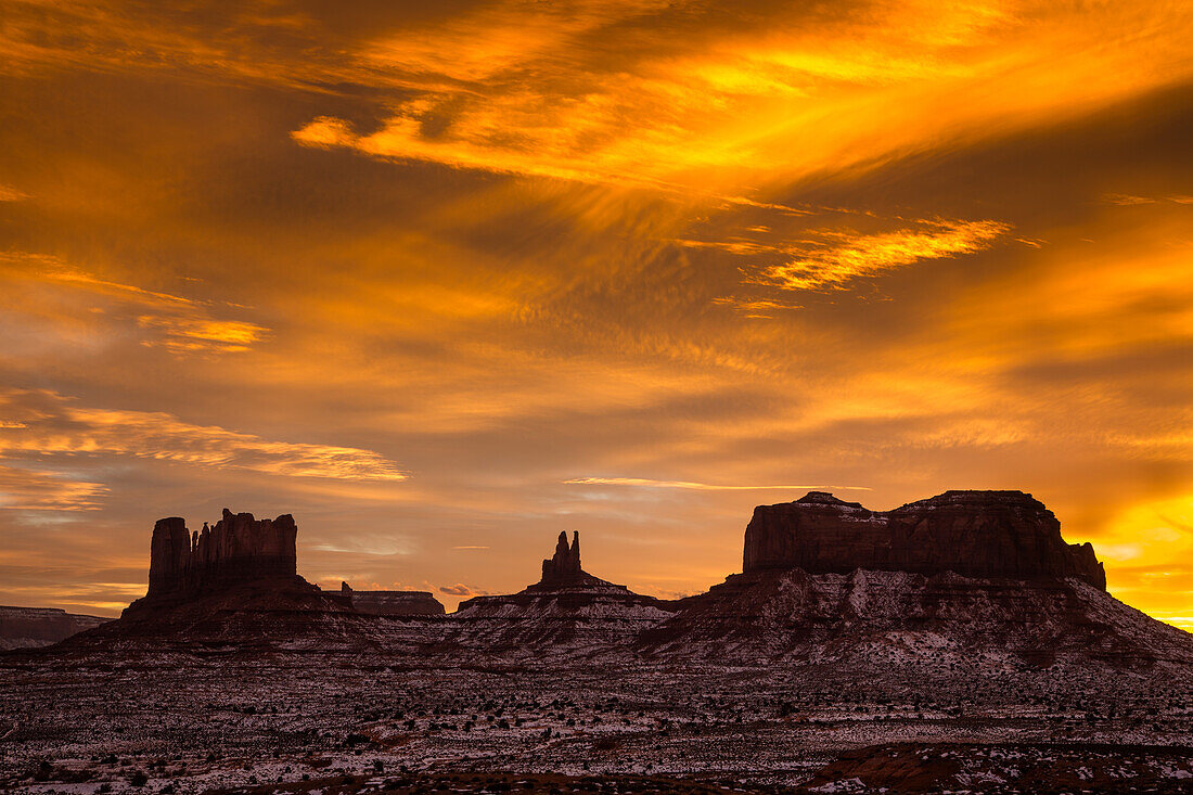 Farbenfroher Sonnenuntergang über den Monumenten von Utah im Monument Valley Navajo Tribal Park in Utah und Arizona. L-R: Castle Butte & die Postkutsche, König auf dem Thron & Brigham's Tomb