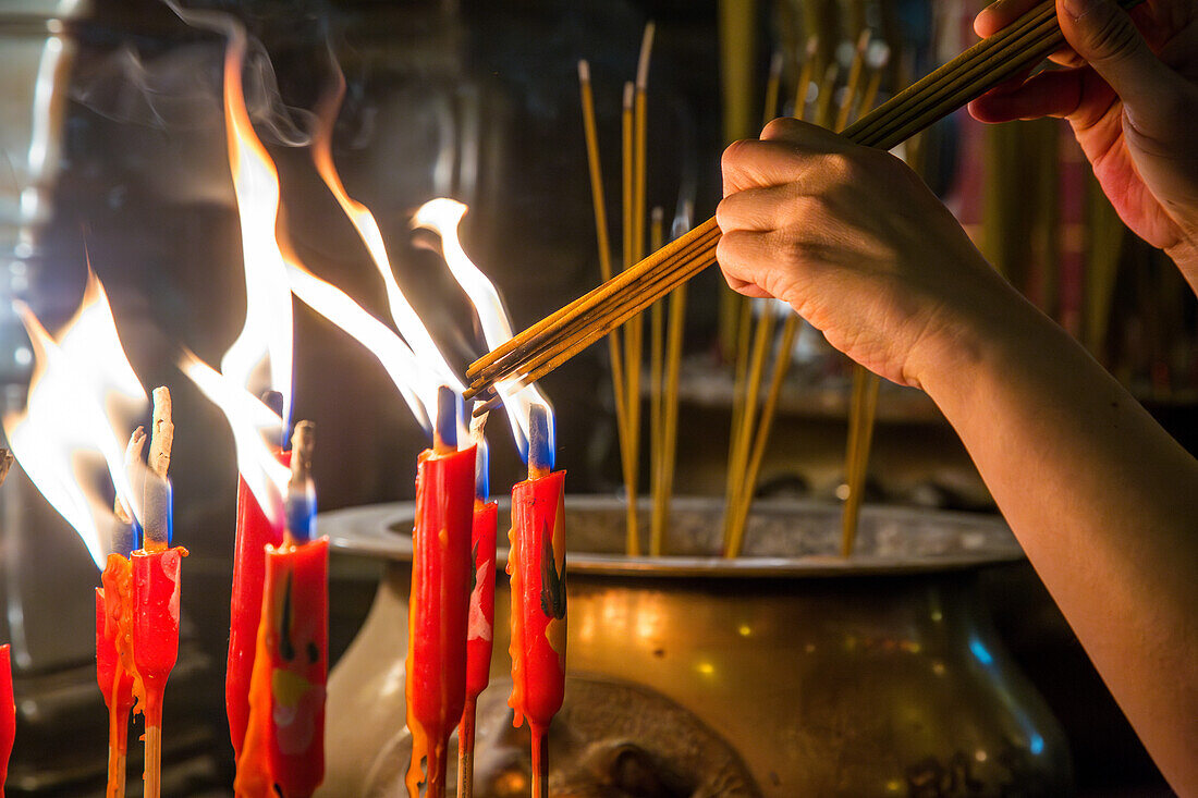 A worshipper lights joss sticks or incense in the Buddhist Man Mo Temple in Hong Kong, China.