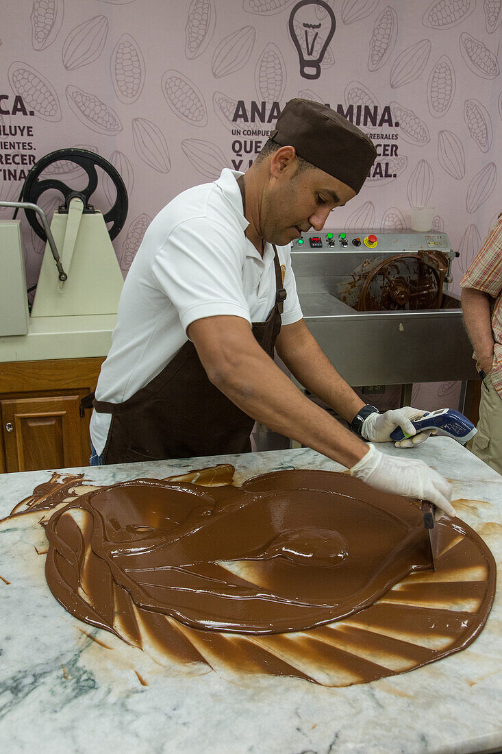 A worker makes chocolate on a cacao plantation tour. Dominican Republic.