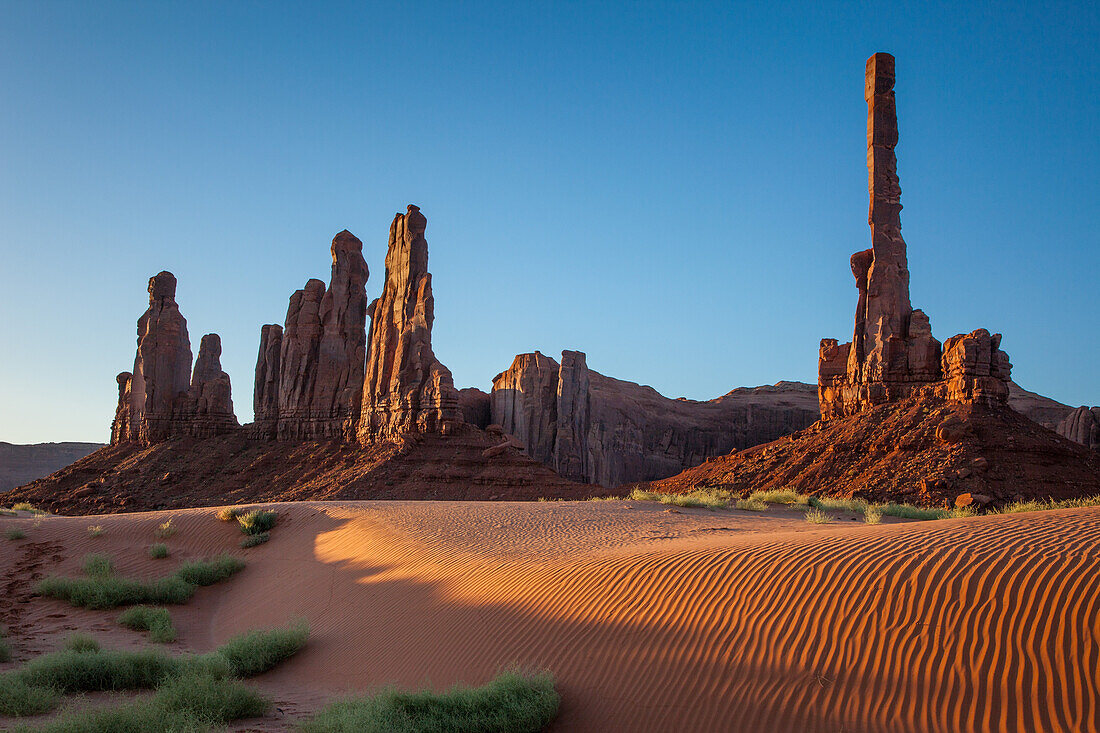 The Totem Pole & Yei Bi Chei with rippled sand dunes in the Monument Valley Navajo Tribal Park in Arizona.