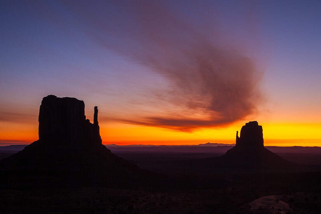 Curved cloud over the Mittens before sunrise in the Monument Valley Navajo Tribal Park in Arizona.