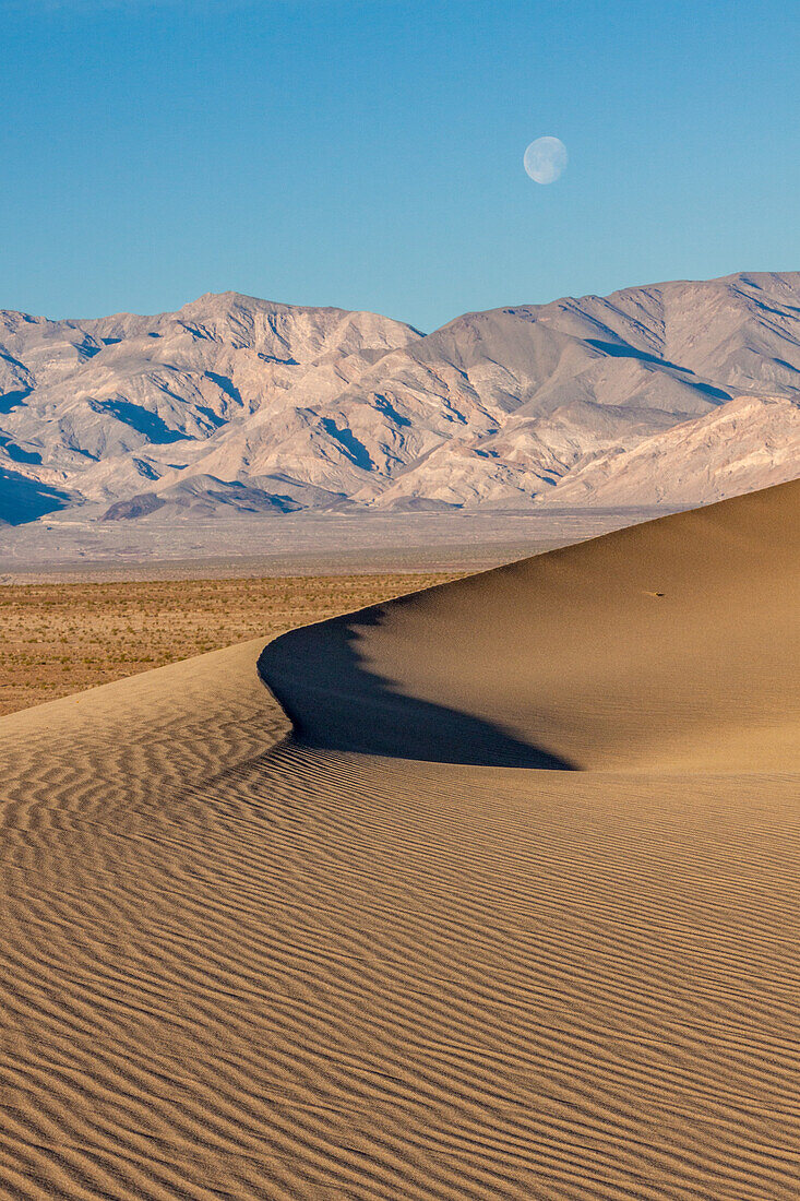Untergehender Mond über den Sanddünen von Mesquite Flat und den Panamint Mountains im Death Valley National Park in der Mojave-Wüste, Kalifornien