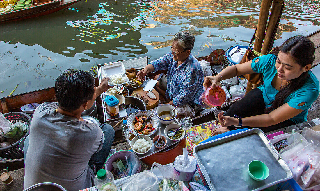 Thailänder essen aus einem schwimmenden Küchenboot auf dem schwimmenden Markt von Damnoen Saduak in Thailand