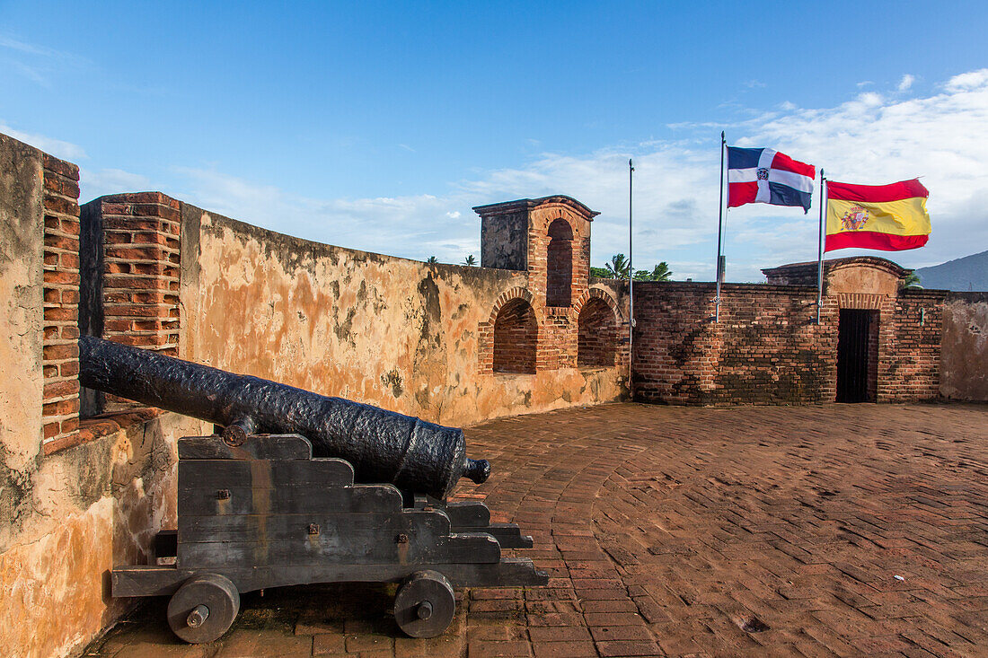 Spanische Kanone und Flaggen der Dominikanischen Republik und Spaniens in Fortaleza San Felipe, heute ein Museum in Puerto Plata, Dominikanische Republik